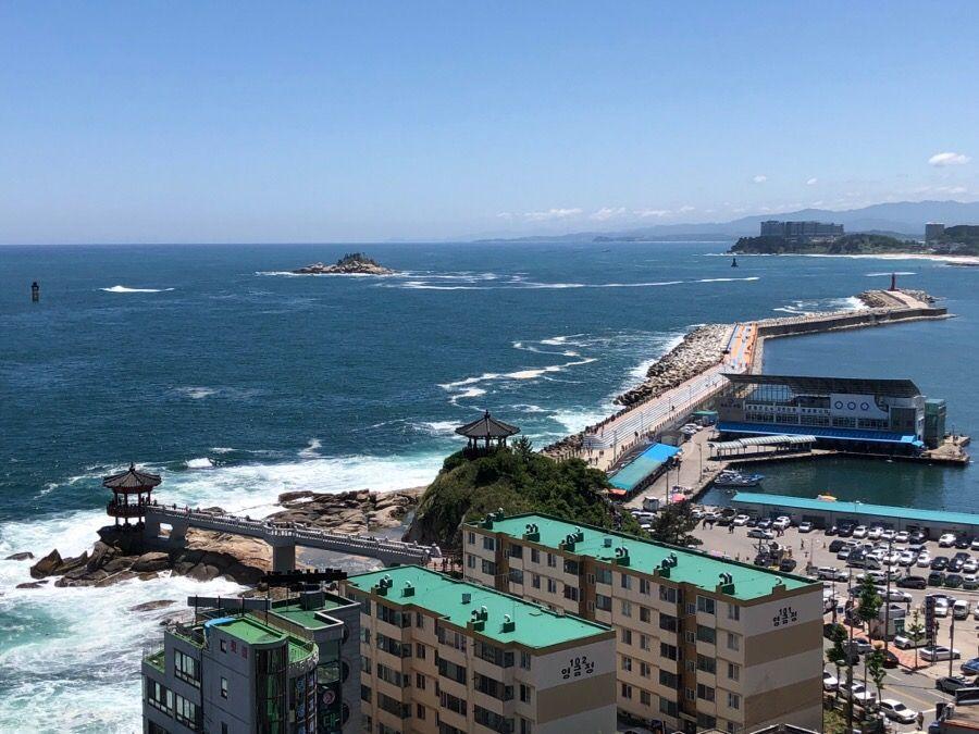 從束草燈塔眺望遠方，波濤洶湧的大海與沿岸城市的壯觀景色。